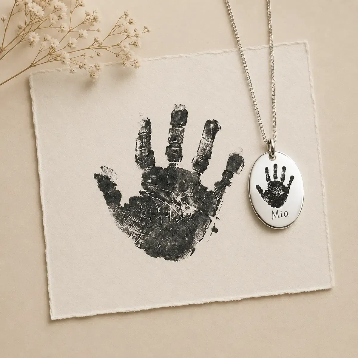 Original painted handprint beside a silver pendant engraved with the prepared handprint