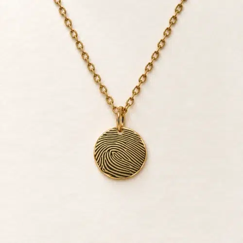 13mm gold coloured stainless steel disc necklace with fingerprint engraving on an ivory background