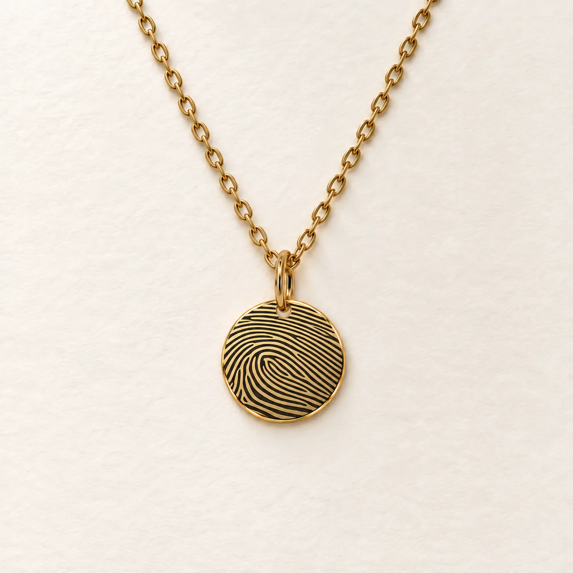 13mm gold coloured stainless steel disc necklace with fingerprint engraving on an ivory background