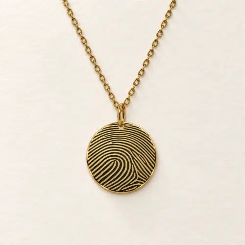 15mm gold coloured stainless steel disc necklace with fingerprint engraving on an ivory background