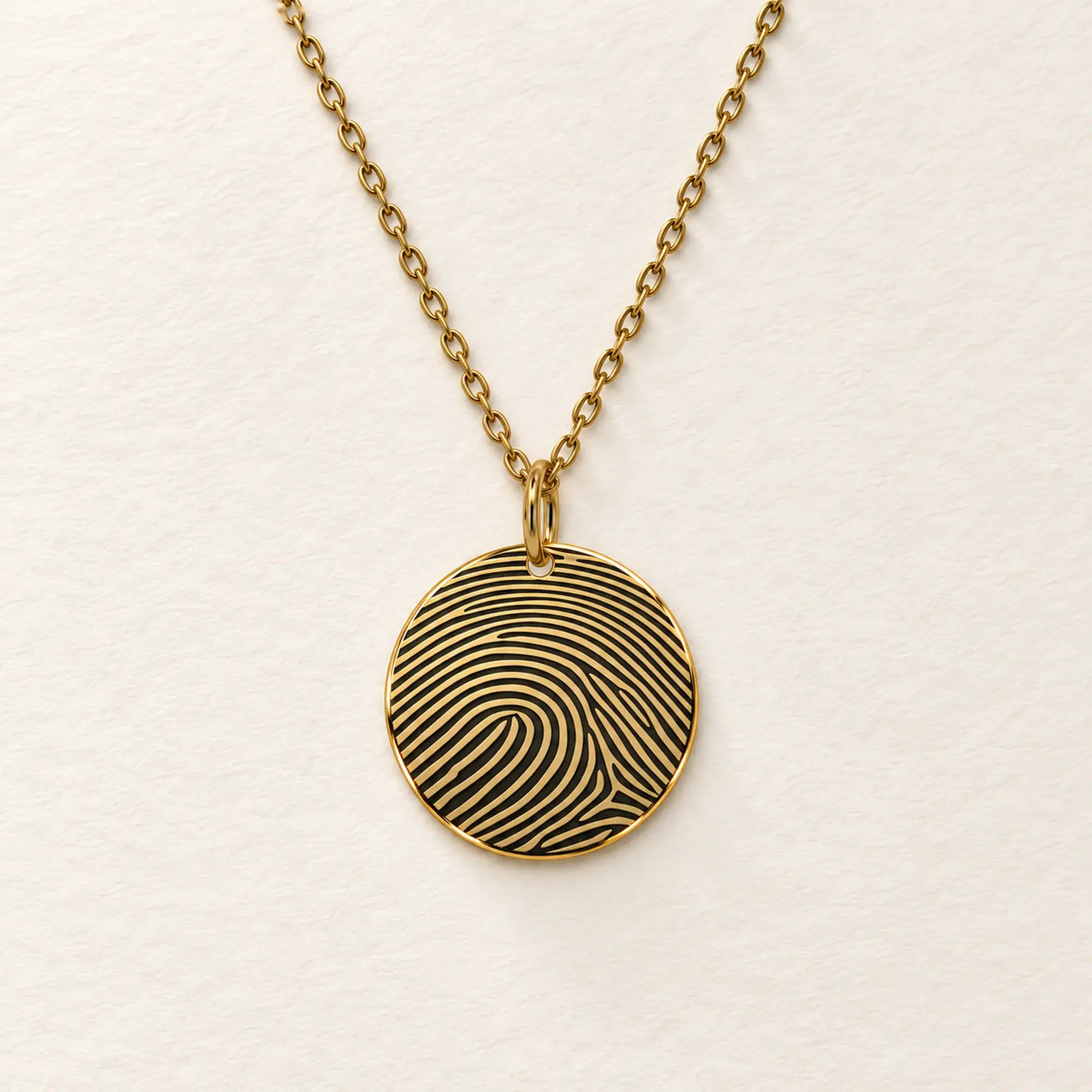 15mm gold coloured stainless steel disc necklace with fingerprint engraving on an ivory background