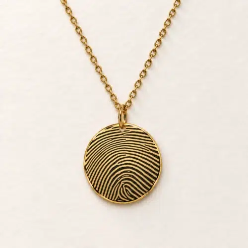 18mm gold coloured stainless steel disc necklace with fingerprint engraving on an ivory background