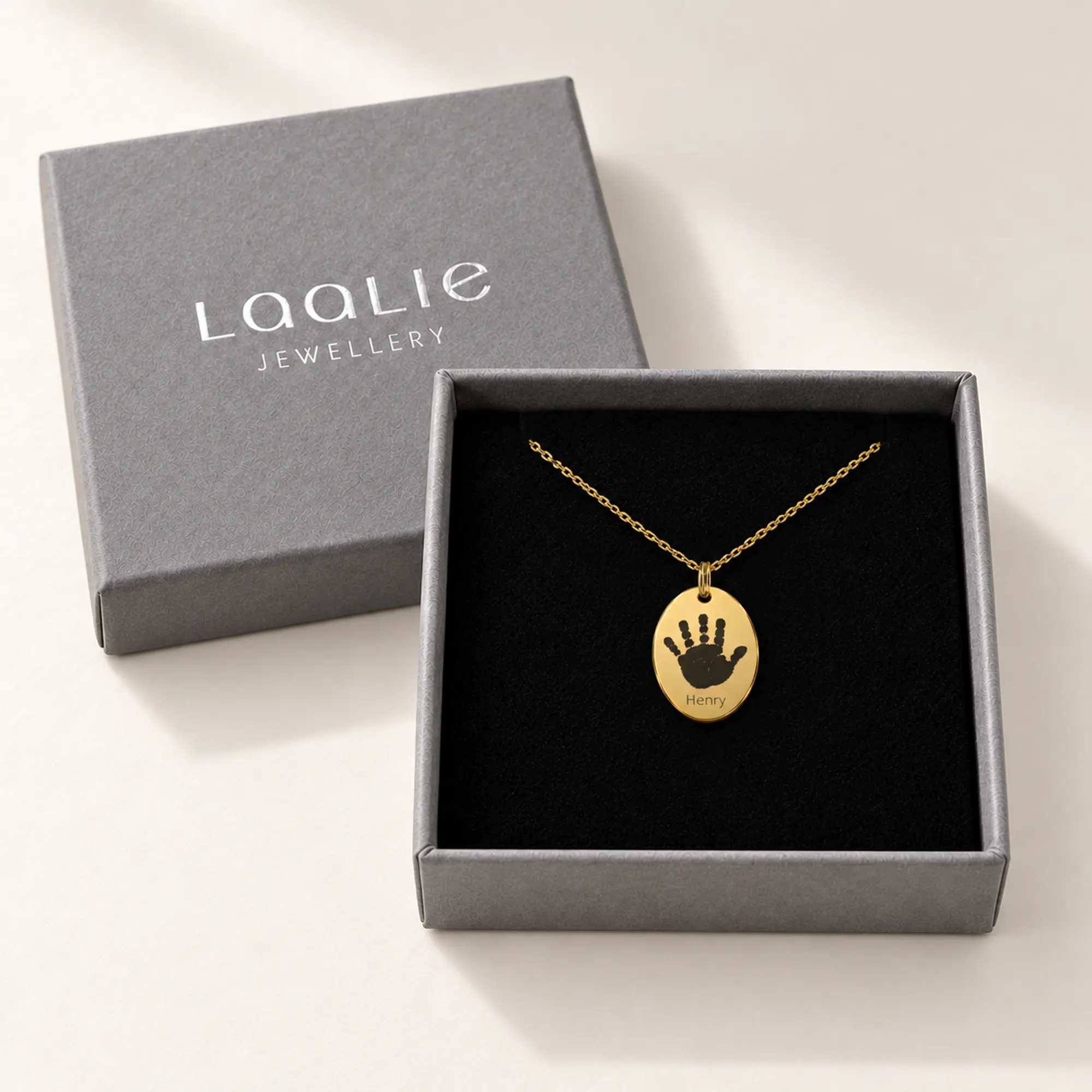 12x18mm gold coloured stainless steel oval necklace with a handprint, in a Laalie gift box.
