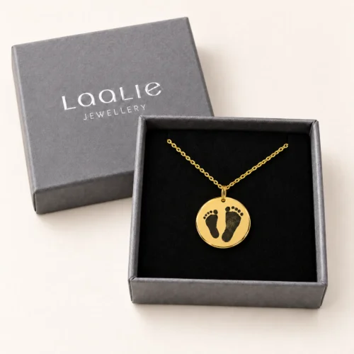 18mm gold coloured stainless steel disc necklace with a pair of footprints, in a Laalie gift box.