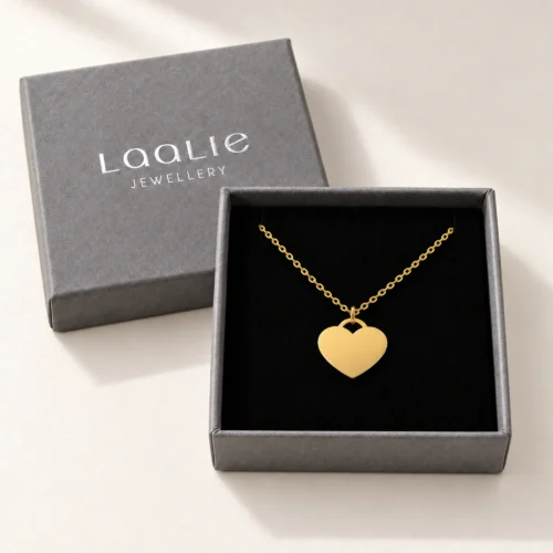 Plain 15mm gold coloured stainless steel heart necklace displayed in an open grey Laalie gift box.