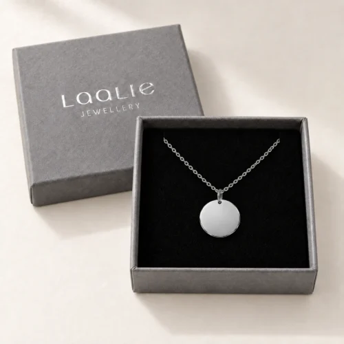 Plain 13mm silver coloured stainless steel disc necklace displayed in an open grey Laalie gift box.