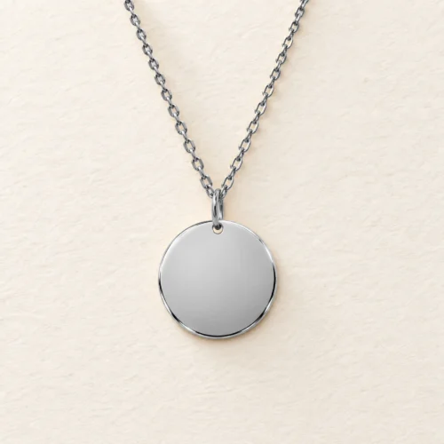 Plain 15mm silver coloured stainless steel disc necklace on a matching chain against a light textured background.