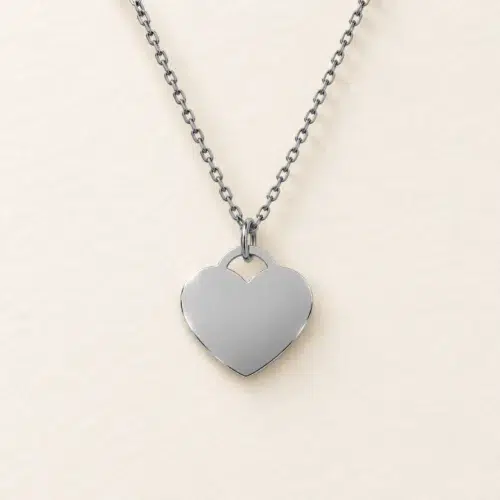 Plain 15mm silver coloured stainless steel heart necklace on a matching chain against a light textured background.