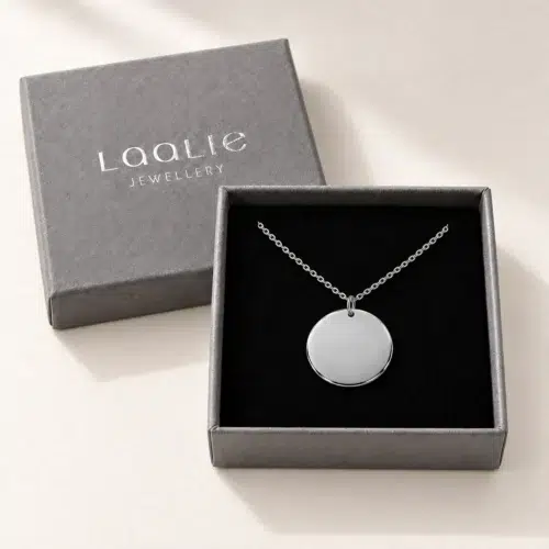 Plain 18mm silver coloured stainless steel disc necklace displayed in an open grey Laalie gift box.