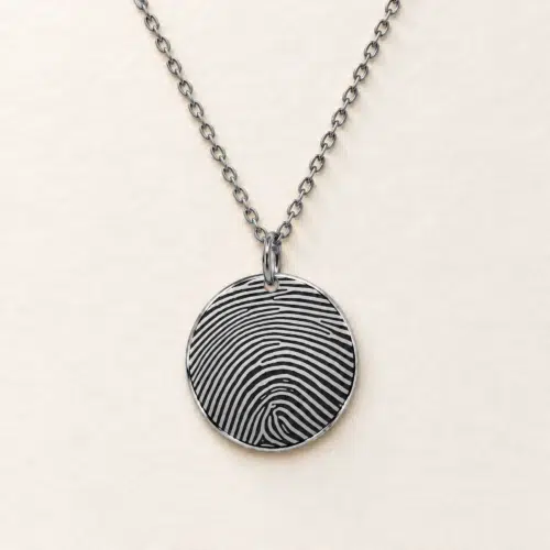 18mm silver coloured stainless steel disc necklace with fingerprint engraving on an ivory background