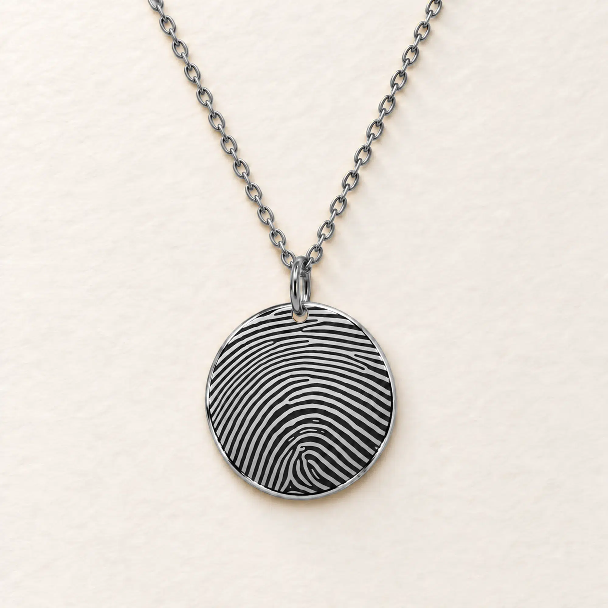 18mm silver coloured stainless steel disc necklace with fingerprint engraving on an ivory background